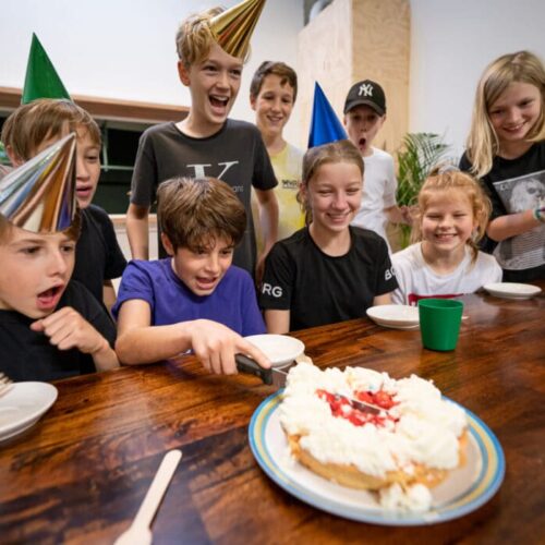 Kinderen die een kinderfeestje vieren en een taart aansnijden