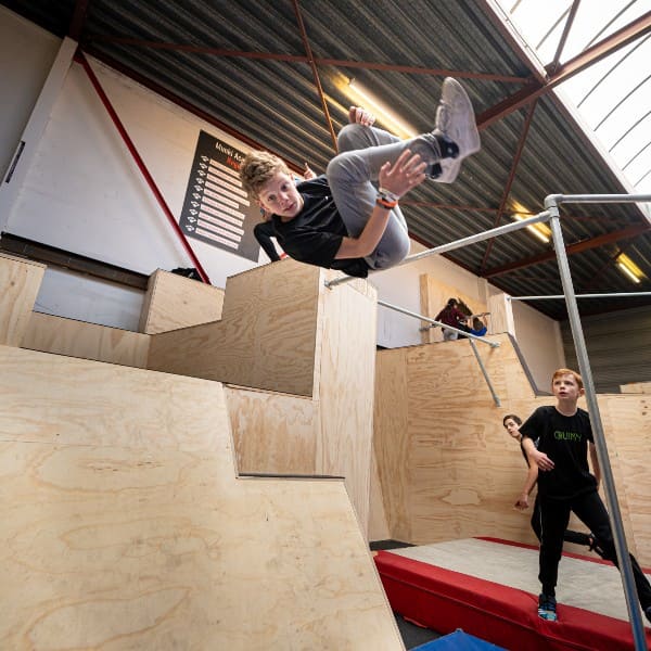 Een sideflip van een blok door een jongen in een freerunhal